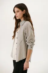 Camisa a rayas verticales color beige y blanco, con cuello clásico, botones marrones y mangas largas.