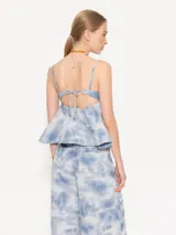 Top celeste con estampado tie-dye, escote recto, breteles finos y corte peplum.
