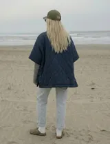 Poncho acolchado color mostaza con cuello alto y abertura frontal con cierre. Presenta un patrón capitoné de formas ovaladas y bolsillos delanteros.