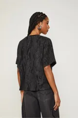 Remera negra con estampado abstracto brillante, escote en V y mangas cortas.