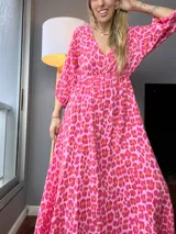 Vestido largo de tela liviana color rosa con estampado animal print en fucsia y naranja. Tiene escote en V, mangas 3/4 abullonadas y cintura elastizada.