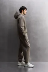 Pantalón jogger color marrón oscuro, corte regular fit, confeccionado en tejido técnico compacto de algodón con elasticidad. Cuenta con cintura elástica ajustable con cordón, bolsillos frontales y bolsillo lateral con cierre de cremallera.