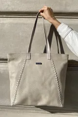 Bolso grande tipo tote de cuero color marrón con costuras decorativas en los laterales, forro interior con bolsillo para celular y bolsillo con cierre. Incluye bolsillo trasero con cierre y correas largas para colgar del hombro.