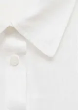 Camisa blanca de lino con cierre de botones, bolsillo de parche en el pecho, manga larga con puños abotonados, diseño recto y cuello camisero.