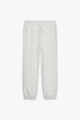 Pantalón jogger color gris claro, de tiro alto con cintura elástica ajustable con cordones, bolsillos delanteros y traseros con solapa, y puños elásticos en el bajo.