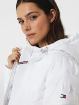 Campera puffer blanca con capucha, cierre frontal con cremallera, bolsillos laterales con cremallera y logo de la marca en la manga izquierda.