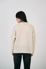 Cárdigan color crema de punto calado, con cuello mao y cierre frontal con cremallera metálica de doble vía.