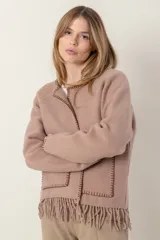 Chaqueta corta color gris oscuro confeccionada en lana merino hervida, con cuello redondo, mangas largas y bolsillos frontales. Presenta detalle de flecos en el ruedo.