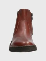 Botín de cuero color marrón con paneles elásticos laterales negros, diseño tipo Chelsea y suela de goma flexible negra con costuras decorativas visibles.