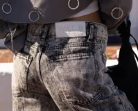 Jean de mujer color gris con efecto acid wash, de tiro alto y corte recto. Presenta costuras verticales en la parte delantera y bolsillos laterales.