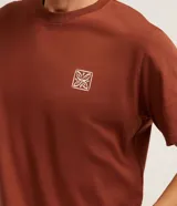 Remera color ladrillo de corte clásico, con cuello redondo y mangas cortas. Presenta un pequeño estampado cuadrado en el pecho.