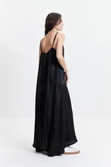 Vestido largo negro con estampado abstracto, de silueta amplia, con breteles finos y escote redondeado. Tiene un frunce sutil en el escote delantero y trasero que genera una caída fluida y relajada.