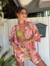 Falda pareo corta con estampado floral grande en tonos rosados, naranjas y beige. Se anuda al costado y tiene un corte asimétrico.