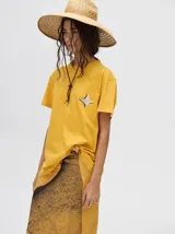 Remera amarilla de corte cuadrado y holgado, con manga corta y estampado de estrella de cuatro puntas en el pecho.