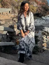 Vestido largo de estilo campesino con estampado de palmeras en tonos blanco y negro, con escote en V y mangas largas abullonadas.