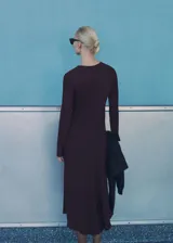 Vestido midi marrón oscuro de tejido ligero con cuello redondo y manga larga. Presenta un diseño evasé con detalle drapeado en la cintura y cierre de cremallera en la parte posterior.