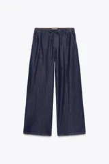 Pantalón de jean azul oscuro, de tiro alto y pierna ancha, con cintura elástica ajustable con cordones y bolsillos delanteros.