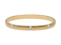 Pulsera rígida dorada con textura acanalada y tres apliques rectangulares con incrustaciones de circonitas.