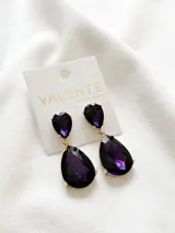 Aros colgantes con forma de lágrima, con cristales facetados de color violeta y engarce dorado.