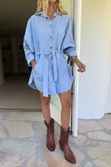 Vestido camisero celeste de algodón con botones de madera, cuello clásico, lazo en la cintura y bolsillos laterales.