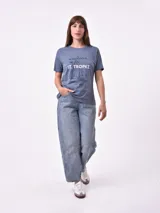 Remera blanca de algodón con cuello redondo y manga corta. Presenta un pequeño bordado en el pecho izquierdo con una figura que parece ser una persona acostada en una tabla de surf o flotador.