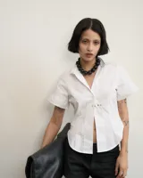 Camisa blanca de poplin, corte al cuerpo, con cuello clásico y cierre frontal con botones.