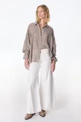 Pantalón jean color beige, de corte recto y tiro alto, con bolsillos delanteros y traseros, y detalle desflecado en los laterales.