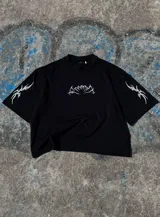 Remera de algodón negra con cuello alto y corte boxy/oversize. Estampa frontal y en mangas con diseño tribal en color blanco.