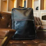 Mochila negra de cuero vacuno con tres compartimentos, uno de ellos acolchado para laptop.