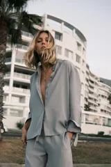 Pantalón de tiro medio color celeste confeccionado en hilatura con mezcla de lyocell. Tiene bolsillos laterales, pinzas en el delantero y pierna ancha. Cierre frontal con cremallera, botón y ganchos metálicos.