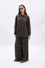 Camisa de manga larga, corte oversize, con cuello camisero y botones frontales. Estampado de patrón orgánico en color dorado sobre fondo negro.