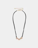 Collar corto con cordón negro y tres dijes de flores esmaltadas color rosa con borde dorado, unidas por eslabones dorados.