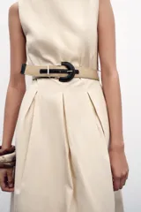 Vestido midi color beige, de popelín, con cuello redondo y sin mangas. Presenta cintura entallada con pinzas, cinturón y falda evasé.