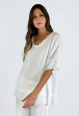 Blusa blanca de lino con escote en V y mangas cortas amplias con detalle de flecos en el ruedo.