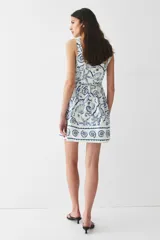 Vestido corto de algodón con estampado de motivos marinos en azul, con costuras estilo corset adelante y atrás. Modelo de cuerpo entallado con breteles anchos, escote cuadrado y cierre oculto con corchete en la espalda. Costura fruncida en la cintura y pollera con vuelo. Cuerpo forrado.