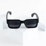 Lentes de sol negros con montura cuadrada gruesa y cristales oscuros.