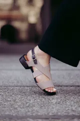 Sandalias de cuero color beige con tiras cruzadas y hebilla lateral. Taco cuadrado color marrón oscuro.