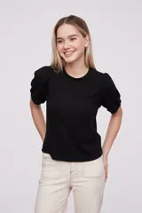 Remera negra ajustada al cuerpo con mangas abullonadas y diseño elegante.