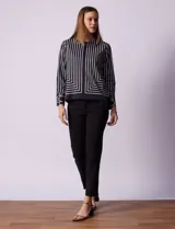Blusa de gasa estampada a rayas verticales blancas y negras, marca Sioni. Tiene espalda con abertura y botón, y mangas largas con puño y botón.