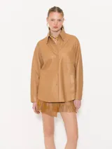 Camisa color camel confeccionada en cuero ovino, con remaches brillantes en las puntas del cuello y cierre con broches forrados en cuero.