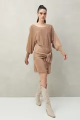 Vestido corto negro de punto con brillo sutil, mangas largas amplias, falda ajustada y lazo frontal en la cintura.