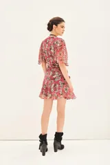 Vestido corto con estampado floral en tonos rojo, gris y blanco. Tiene escote en V, mangas cortas con volados, frunces en el delantero y espalda, bolsillos delanteros y cierre invisible.