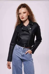 Campera corta de cuero sintético negro, con cuello solapa, cierre frontal asimétrico con cremallera, bolsillos laterales con cremallera y cinturón con hebilla.