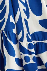 Vestido midi de viscosa con estampado floral azul sobre fondo blanco, cuello camisero, tapeta de botones oculta, mangas raglán largas con puños sencillos y costuras fruncidas en la falda.