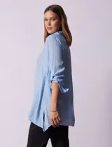 Camisa color beige claro, de corte recto y mangas 3/4 con botón para sujetar.