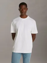 Remera blanca de algodón regenerado con cuello redondo, mangas cortas y corte regular. Estampado frontal con monograma de Calvin Klein en capas. Detalles distintivos de Calvin Klein Jeans.