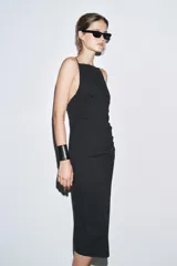 Vestido midi negro de tirantes finos, con cuello halter, detalle de drapeado y cierre con cremallera oculta.