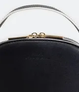 Bolso pequeño cruzado de forma redondeada, color negro con detalles en blanco. Tiene correa ajustable, tirante de mano y cierre de cremallera.
