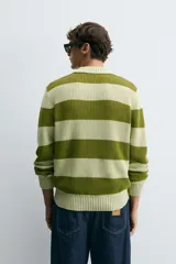 Sweater de punto a rayas horizontales anchas color verde oliva y verde claro, con cuello polo y mangas largas. Tejido en hilatura con algodón y lino, con terminaciones en rib.