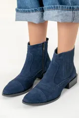 Bota corta azul de gamuza con puntera redondeada y detalles de perforado. Tiene cierre lateral y taco bajo.